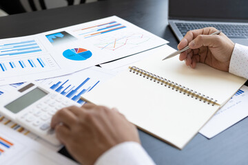Close-up businessman holding a pen writing notes on a notepad. Financial planning and accounting concepts.