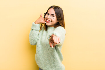 pretty hispanic woman smiling cheerfully and pointing to camera while making a call you later...
