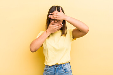 pretty hispanic woman covering face with both hands saying no to the camera! refusing pictures or...
