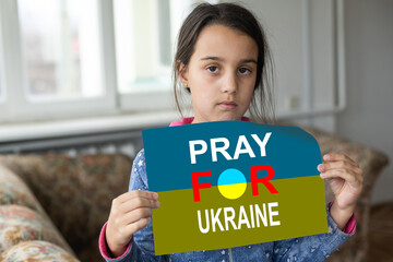 Sad little girl covered with Ukraine flag. Concept of standing with Ukrainian nation in war with...