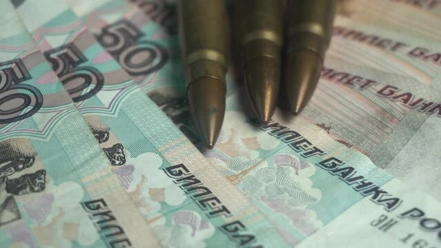 Kalashnikov AK 47 Bullets on Russian Ruble Banknotes, War and Economy Concept, Close Up