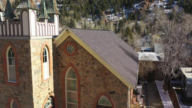 Flight above a village in mountains. 4k. Aerial view of houses, pine tree , snow land and mountain.