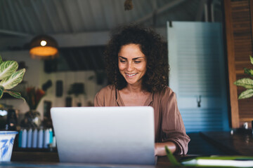 Happy Caucasian woman enjoying time for social networking on modern laptop computer using WIFI...