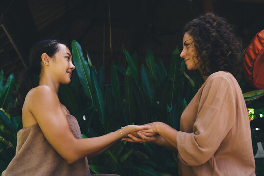 Female psychiatrist's hands holding hands of patient together spending weekend daytime for meditation therapy and holistic retreat healing, diverse women communicate about trust and support