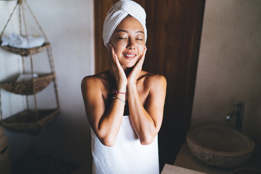 Pretty Korean woman in white towel enjoying time for herself during weekend lazy day in home, carefree female spending leisure for cosmetology cleansing and moisturize for skin care and pleasure