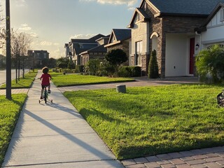 little boy riding bike in his neighborhood on the sidewalk in lake nona florida in orlando  - obrazy, fototapety, plakaty