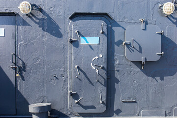 Metal door with porthole on wall with pipes, valves and rivets. Bunker close entrance. Ship or...