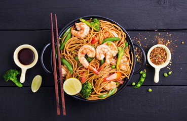 Stir-fried spaghetti or stir-fry noodles with vegetables and shrimp in a black bowl. dark background, top view