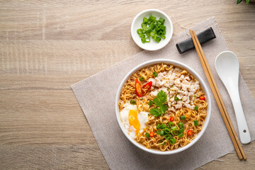 Instant noodle soup with minced pork and boiled egg in white bowl on wood table.Top view