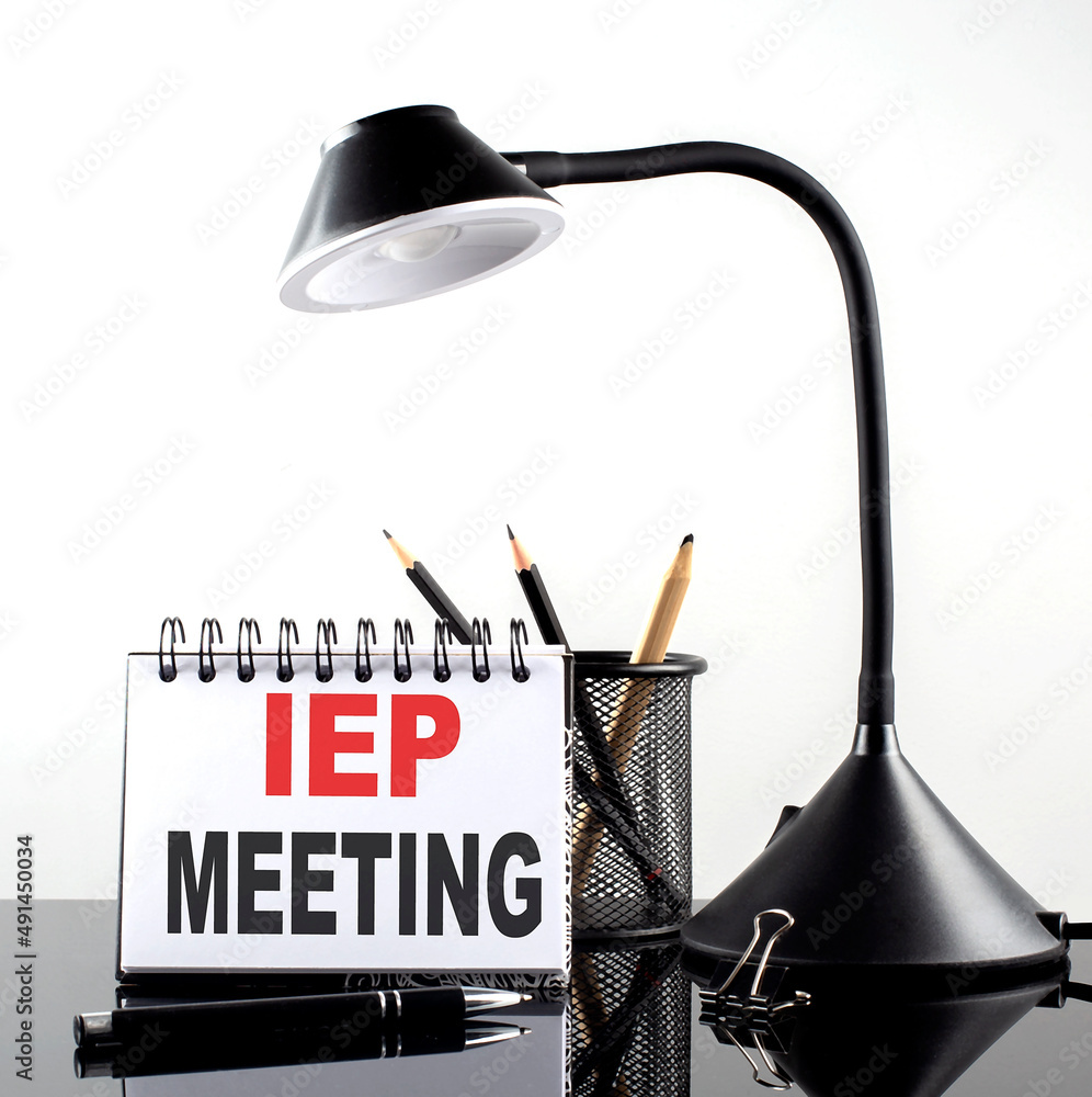 Poster iep meeting text on notebook with pen and table lamp on the black background