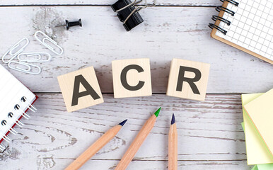 ACR text on wooden block with office tools on the wooden background