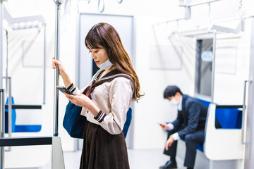 鼻だしマスクをして電車にのる女子高生