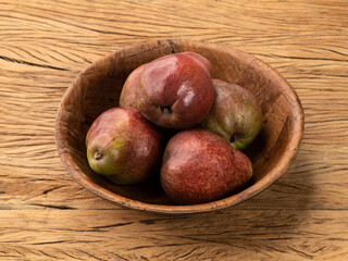 Red pears in a bowl over wooden table