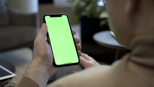 Smartphone with chroma key green screen at office, scrolling through social media or online shop - internet, communications concept close up 4k template
