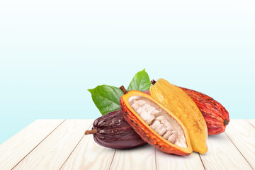 Group of various types of fresh cocoa fruit and green leaf isolated on wooden table with blue ...