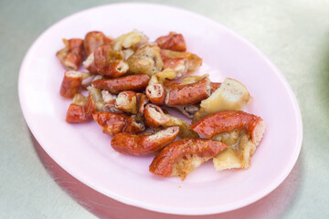 Tender and delicious grilled pork patties sliced ​​in pink plates on the table taste good, Northeast’s food of Thailand (Isaan food) is a street food in Thailand.