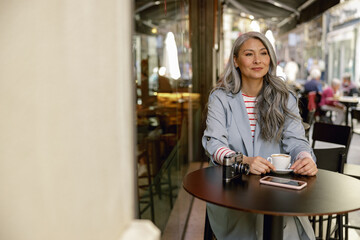 Good looking mature female relaxing at street cafe