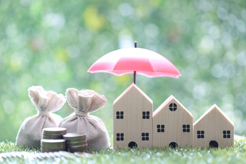 Protection, Coins money in the bag under the umbrella and model house on natural green background, Finance insurance and Safe investment concept