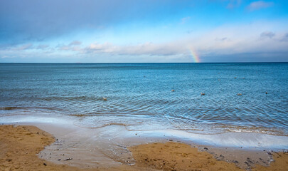 Panoramic winter view of Baltic sea with beach and rainbow over maritime horizon offshore Gdynia...