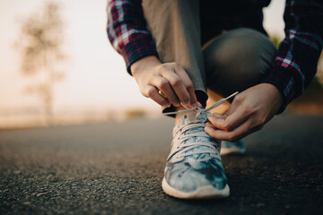 young woman  tying her shoelaces at sunset.