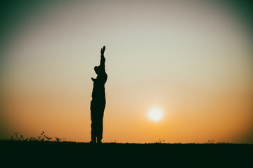 Silhouette of the woman standing lonely at the river during beautiful sunset