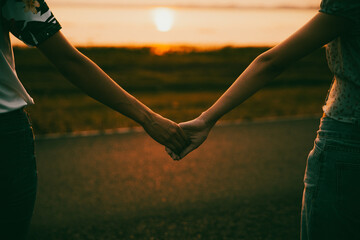 Young couple in love holding hands looking in the sunset