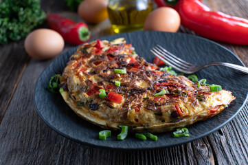 Omelette or omelet with vegetables, fried with red onions, bell peppers and topped with chives