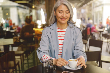 Asian woman having cup of coffee in cafe