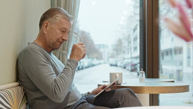 Businessman sitting in cafe working on digital tablet