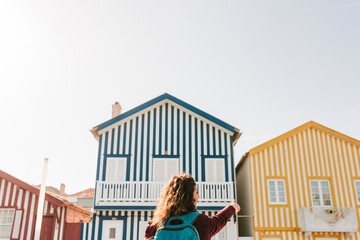 back view of backpacker woman in front of colorful houses.promenade of Costa Nova, Aveiro, Portugal