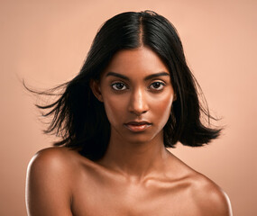 And then... the wolves came. Portrait of a beautiful young woman posing against a brown background.