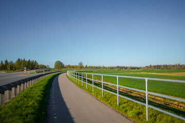 Fototapeta na wymiar Beautiful spring landscape of rural area with asphalt road. Seasonal scenery of Northern Europe.