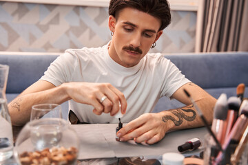 Brunette man doing manicure at home while preparing new look for himself