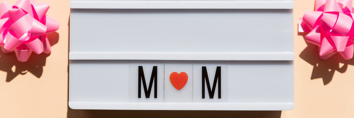 Happy Mother's Day card concept. I love mom, red hearts, text in a light box. Copy space, top view, flat lay.White lightbox with words ans symbols.