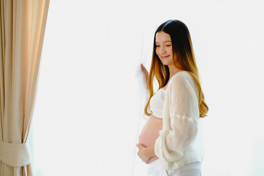 Young beautiful pregnant woman standing of happy pregnant woman with big belly at window. Smiling pregnant woman. white background..