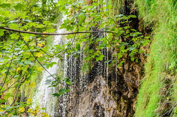 Rushing Water on the Great Waterfall of Plitvice Lakes National Park, Croatia, on a Sunny Day. Waters Flow over Steep Mossy Rocks and Folliage.