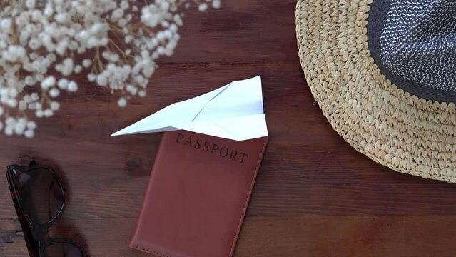Flat lay travel concept video. White paper aeroplane flies into shot.  Holiday and vacation items surround frame edges. 4k travel footage