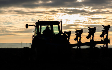 Fototapeta na wymiar Tractor on the field during sunset.