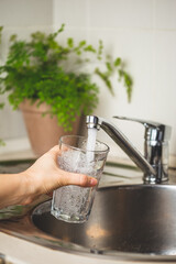 Female hand filing a glass with clean tap water