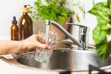 Female hand filing a glass with clean tap water