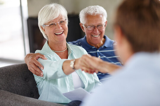 Ill Shake On That.... Over-the-shoulder Shot Of A Financial Advisor Meeting With A Senior Couple At Their Home.