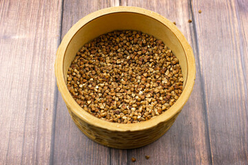 Buckwheat natural. A grain of buckwheat. Buckwheat in a wooden jar. Buckwheat and palms.