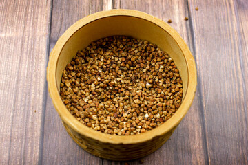 Buckwheat natural. A grain of buckwheat. Buckwheat in a wooden jar. Buckwheat and palms.