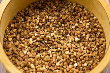 Buckwheat natural. A grain of buckwheat. Buckwheat in a wooden jar. Buckwheat and palms.