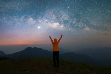 Portrait of Asian woman, a tourist, travel at Doi Tung, Chiang Rai, Thailand with mountain hills, the milky way in galaxy with stars at night. Universe space landscape background. People lifestyle.
