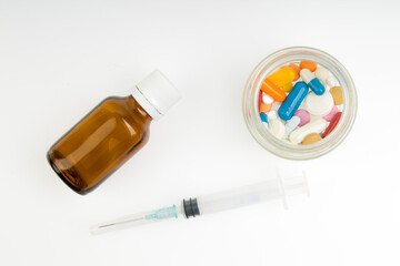 Pills, vitamins and syringe for injection with medications isolated on white background.