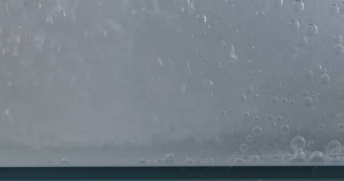 fizzy soda gets filled into full water tank or aquarium shot at 60 fps creating big underwater swirl, water splash against glass panel in 4k. 