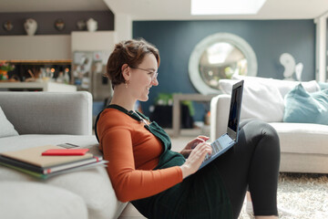 Young woman with laptop working from home in living room