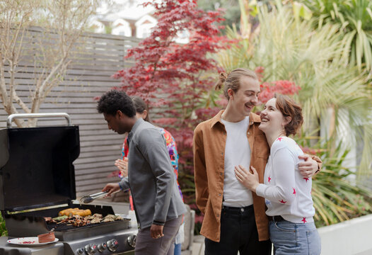 Happy young couple enjoying patio barbecue with friends