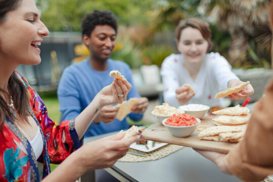 Friends enjoying pita bread and dip on patio